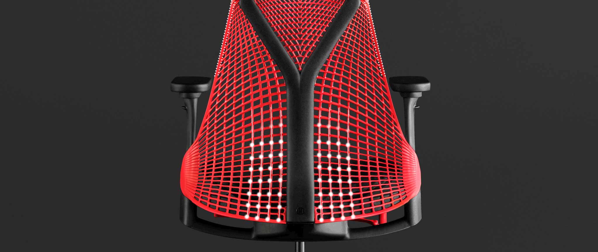 Bakifrånvy av en röd och svart Sayl-gamingstol från Herman Miller, överlagrad med vit grafik som framhäver det fjädrande ryggstödet.