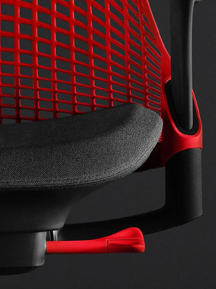 Närbild framifrån av en röd och svart Sayl-spelstol från Herman Miller, som visar den konturerade sittdynan och det röda ryggstödet.