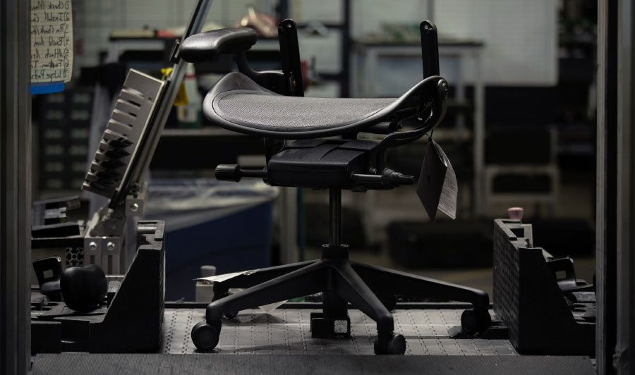 Bas och sits på svart Aeron-spelstol från Herman Miller i en fabriksmiljö.