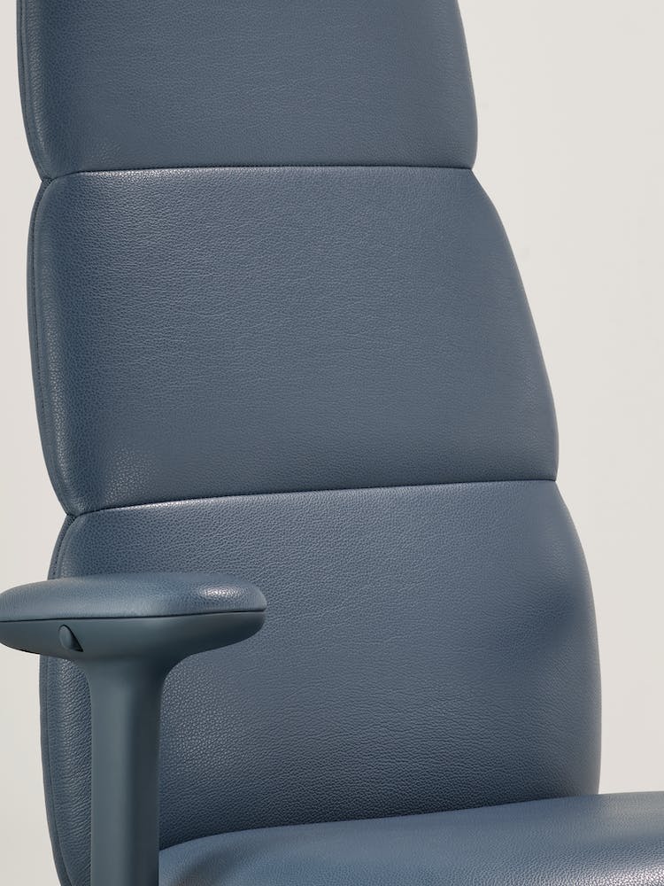 Närbild av en blå läderkontorsstol Asari från Herman Miller, som visar den integrerade, interna Posturefit-tekniken.
