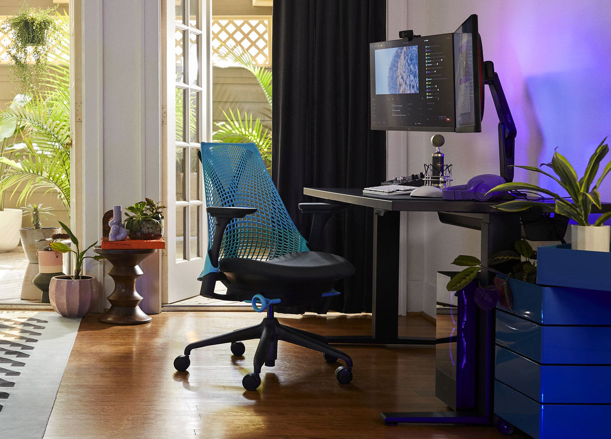 Foto av Friskks spelutrustning hemma bestående av en Sayl-gamingstol i svart och havsblått med ett Nevi-gamingbord i svart.