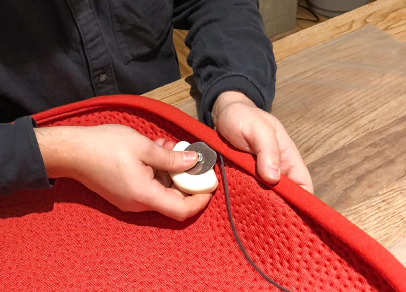 En person som tillverkar en röd tygklädsel till en Herman Miller Zeph-kontorsstol.