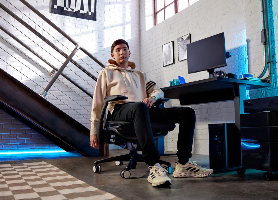 Bild på Jelty från G2 Esports-teamet sittande i G2 Embody-stolen med ryggen mot spelutrustningen, inklusive Nevi-spelbord i svart med Ollin-skärmar