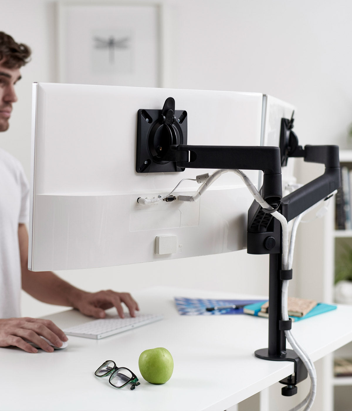 En svart CBS Lima-skärmarm för två skärmar som håller två skärmar på ett sit-stand-skrivbord.