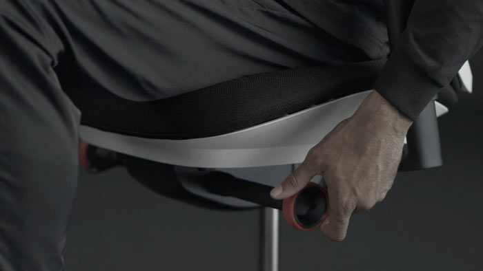 En video av en person som sitter i en vit och svart Vantum-spelstol från Herman Miller och sträcker sig bredvid stolen för att justera lutningsbegränsaren.