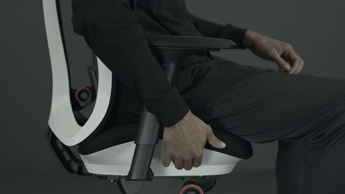 En video av en person som sitter i en vit och svart Vantum-spelstol från Herman Miller och sträcker sig bredvid stolen för att justera sittdjupet.