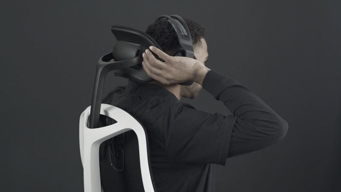 En video av en person som sitter i en vit och svart Vantum-spelstol från Herman Miller och sträcker sig bakom stolen för att justera nackstödet.