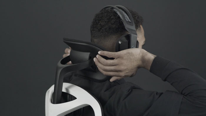 En video av en person som sitter i en vit och svart Vantum-spelstol från Herman Miller och sträcker sig bakom stolen för att justera nackstödet.