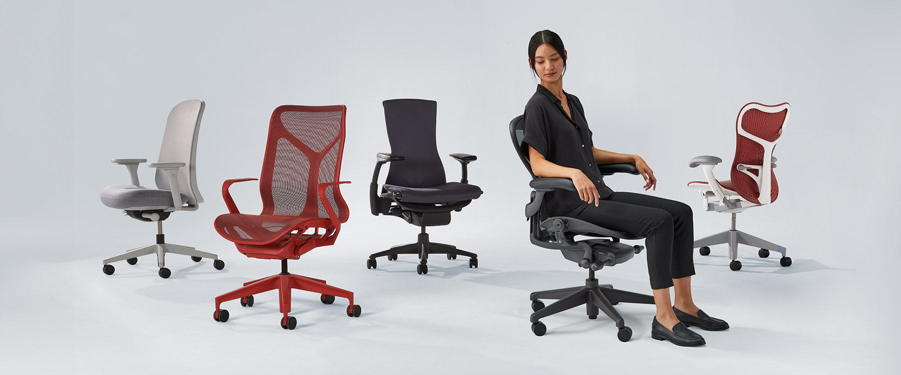Foto av Herman Miller-stolar uppradade, inklusive Verus mineralvit och grå, Cosm med mellanhög rygg i canyonröd, Embody svart, Aeron grafit med en kvinna sittande och Mirra 2 i cordovanröd