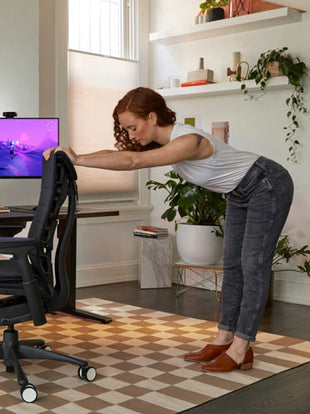 Foto av Dr Lindsey Migliore lutad mot ryggstödet på Embody-gamingstolen och gör rygg-, axel- och bensträckningar