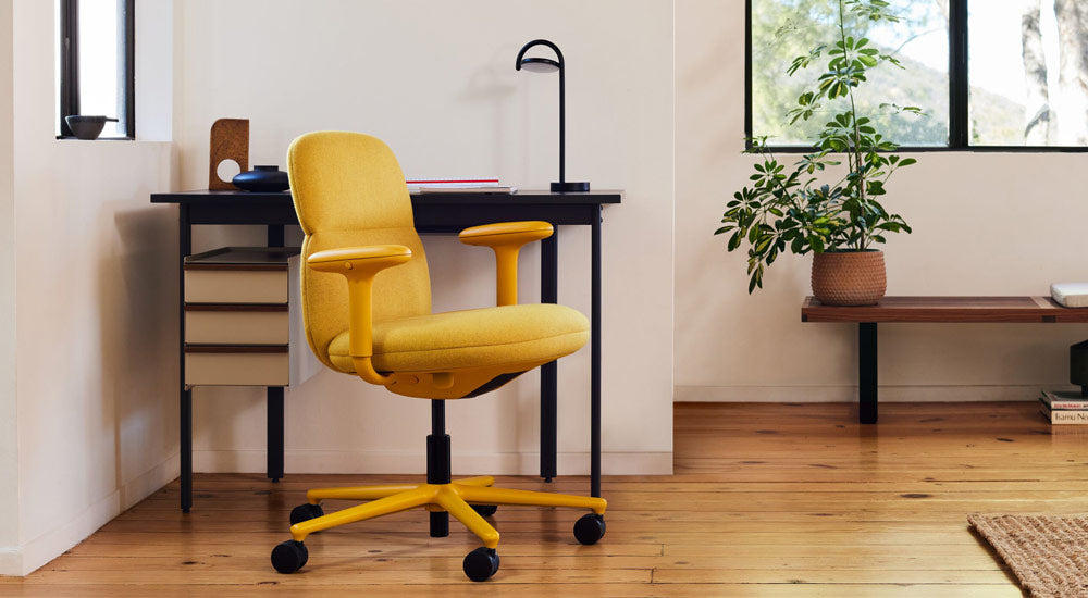 En gul Asari-kontorsstol från Herman Miller, klädd i Clarion Luce-tyg från Maharam – med ett Mode-skrivbord och en Marselis-lampa.