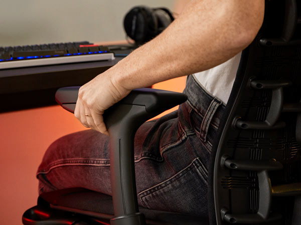 Närbild av Dr Lindsey Migliore som justerar armstödet på Embody gamingstol