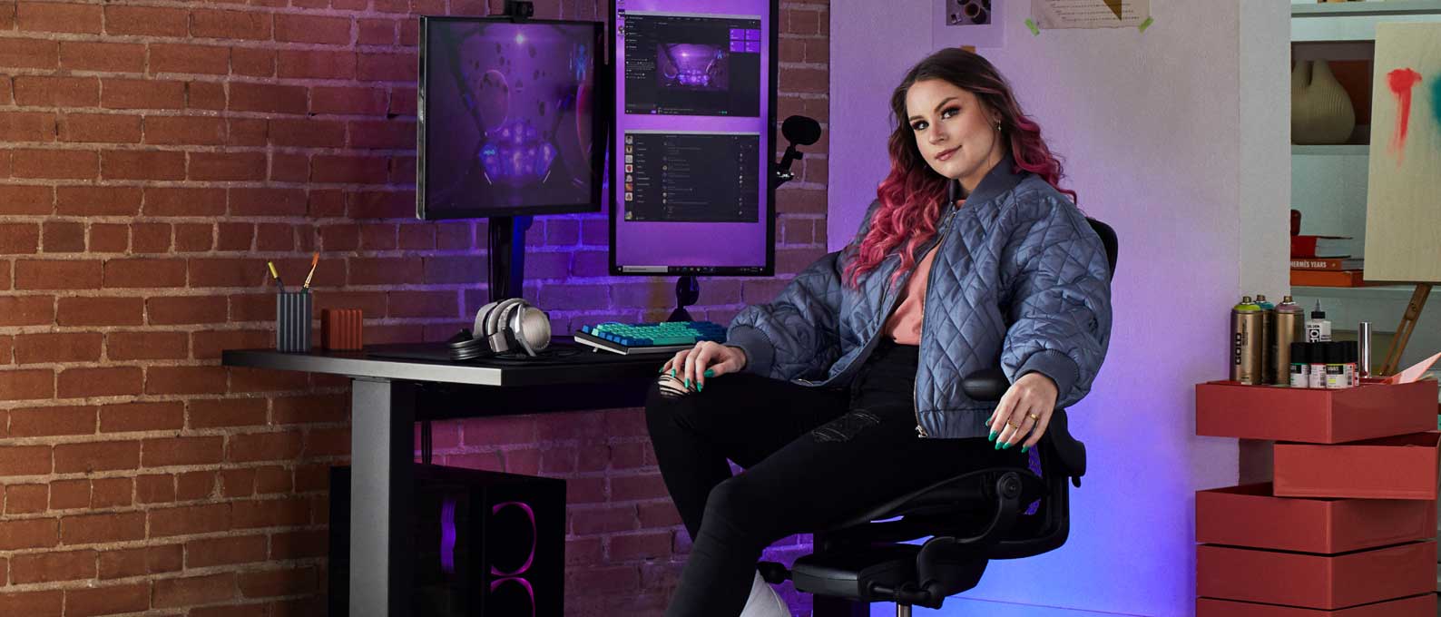 Foto av gamer Electra som sitter vänd mot kameran i Aeron gaming onyx black framför Nevi gaming desk i svart med Ollin-monitor