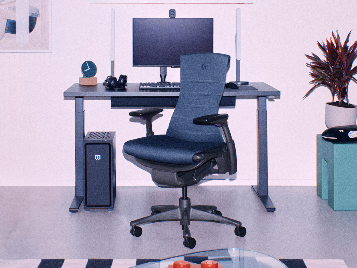 Herman Miller svart Embody gamingstol med svart Nevi sit-stand gamingbord med gamingutrustning inklusive dubbla bildskärmar