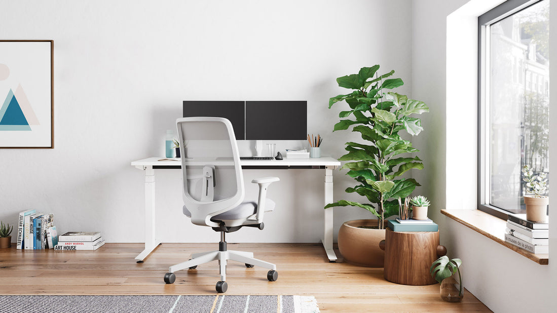 Ett vitt Nevi sit-stand-skrivbord från Herman Miller som en del av ett ljust hemmakontor.