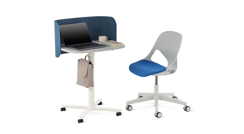 Ett vitt Passport-arbetsbord från Herman Miller med en blå Passport-skrivbordsskärm. Placerat bredvid en grå och blå Zeph-kontorsstol.
