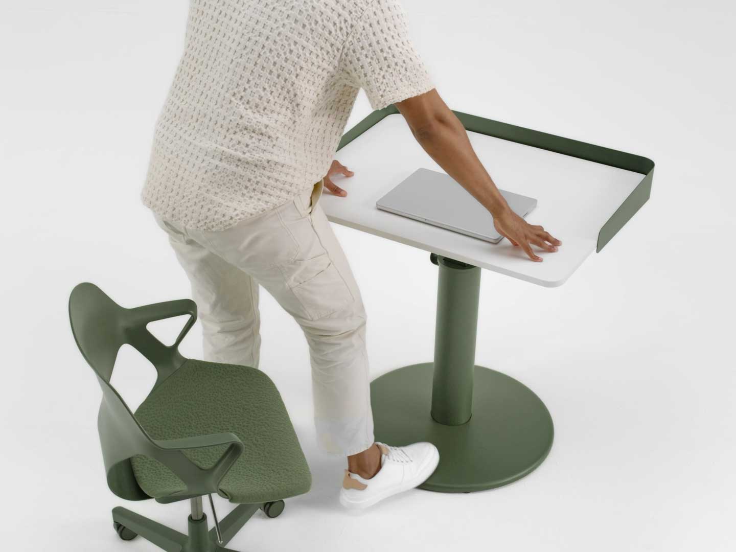 Een blauwe Cosm-bureaustoel van Herman Miller, geplaatst voor een zwart en essenhouten OE1-sta-bureau van Herman Miller, met een optionele omhullende scherm.