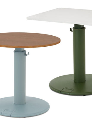 Två OE1-stående skrivbord från Herman Miller, ett med rund bordsskiva i valnöt och blå bas, och ett med rektangulär vit bordsskiva och grön bas.