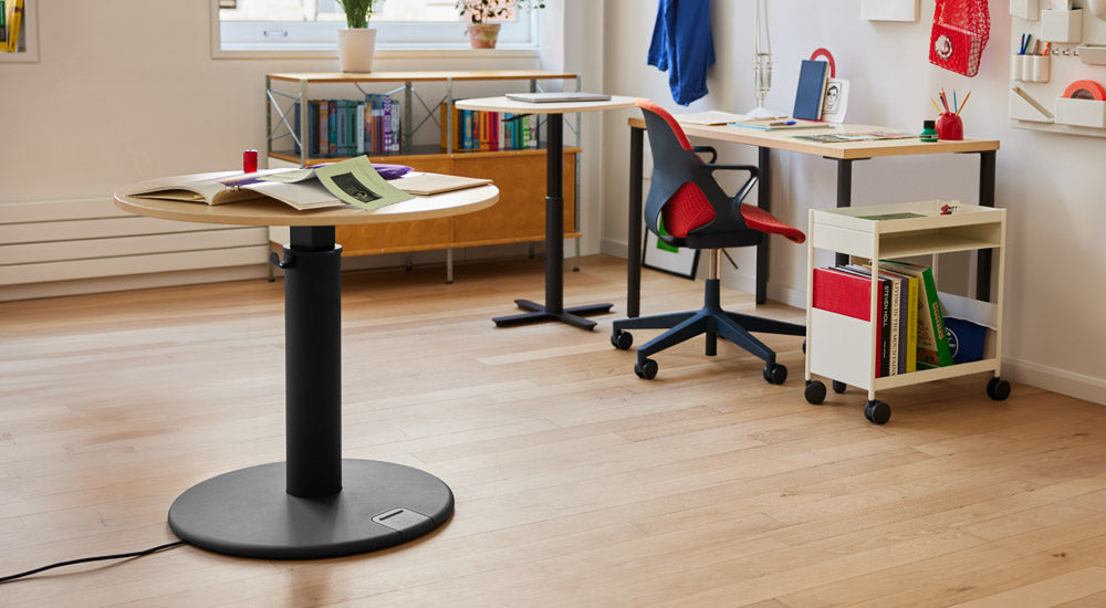 Ett färgglatt hemmakontor med ett svart och askfärgat OE1-stående skrivbord från Herman Miller, ett Passport-arbetsbord, ett OE1-skrivbord, en svart och röd Zeph-stol och en vit OE1-vagn.