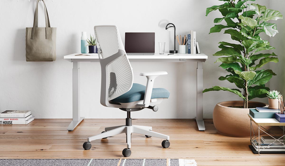 En vit och blå Verus-kontorsstol från Herman Miller, placerad framför ett vitt Nevi-ståbord.