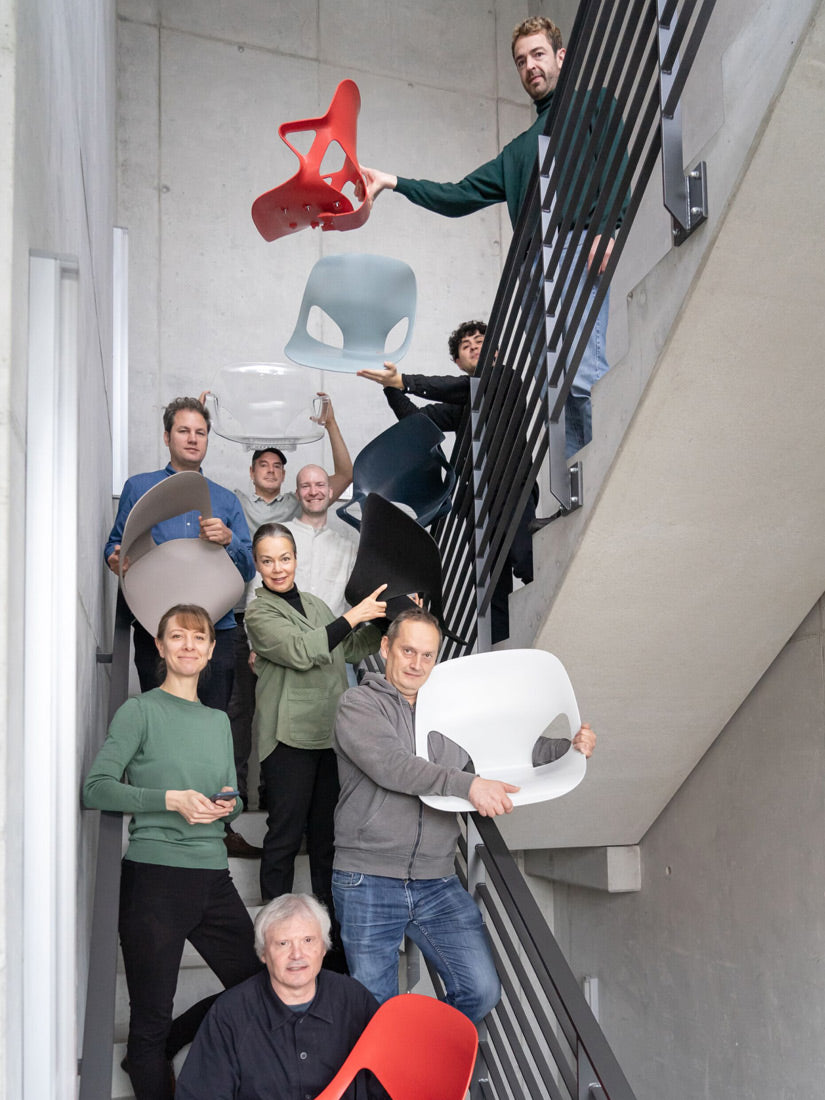 Foto av medlemmarna i designteamet Studio 7.5 i ett trapphus, några av dem håller i olika delar av stolen Herman Zeph som de har designat.