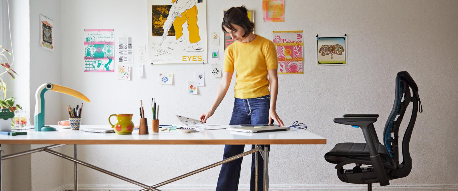 Illustratören, målaren och författaren Molly Rose Dyson står i sin ateljé med en Embody-spelstol i svart och cyanblått