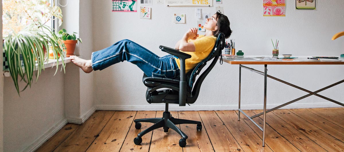 Illustratören, målaren och författaren Molly Rose Dyson i sin ateljé, sittande lutad i en Embody-spelstol i svart och cyanblått