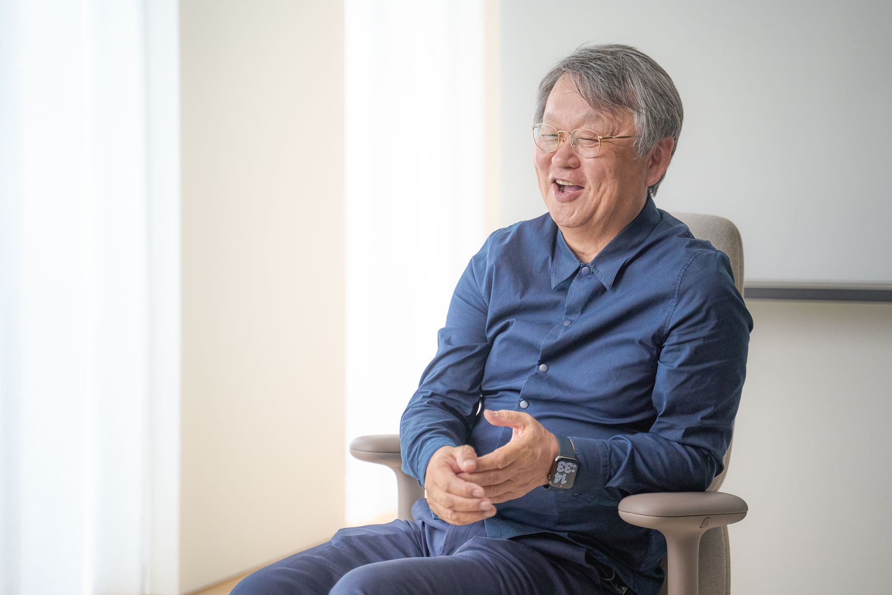Glad bild av Naoto Fukasawa sittande i en Asari kontorsstol