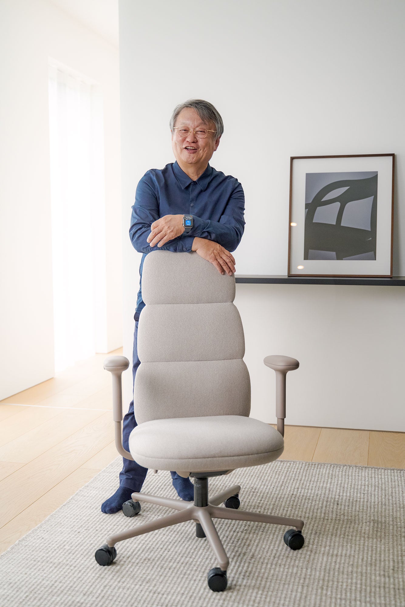 Foto av Naoto Fukasawa stående bakom en Asari-kontorsstol i alpinvit
