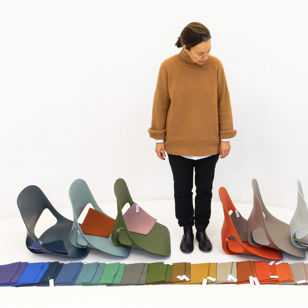 Designer från Studio 7.5 tittar ner på golvet på materialprover och Zeph-stolar i olika färger