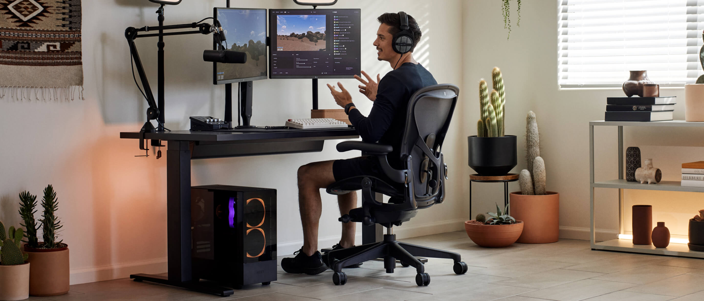 Spelaren Xaryu med händerna i luften spelar spel vid sin Herman Miller-uppsättning i Aeron-gamingstol med Nevi-gamingbord och Ollin-dubbla monitorarmar