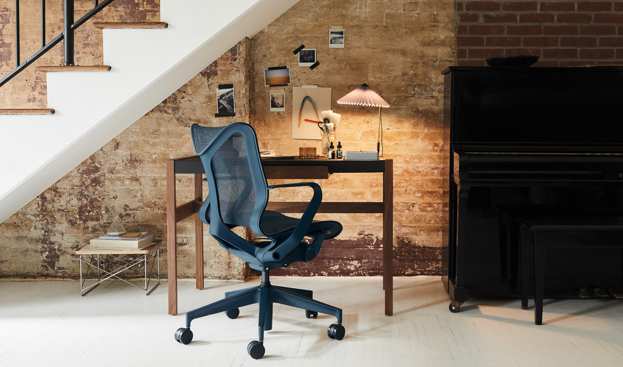 En blå Herman Miller Cosm-kontorsstol placerad framför ett skrivbord och under en trappa i en hemmiljö.
